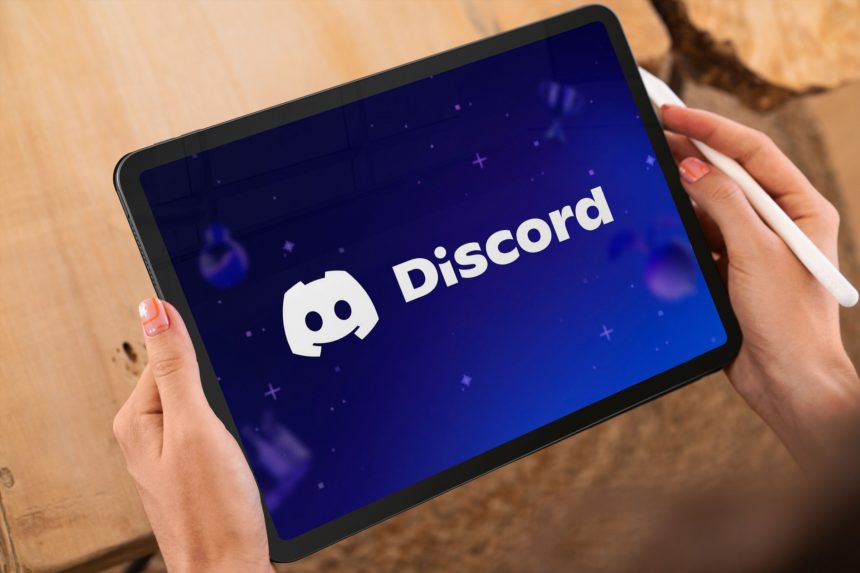 Hands holding tablet displaying discord social media app, popular communication platform for communities and gamers
