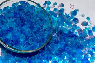 Silica gel crystal granules in a glass bowl on white background.side angle view and close up.It is used in packaging and storage of electronic equipment, camera and optics.