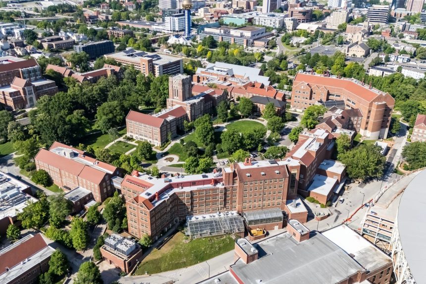 An aerial view of the University of Tennessee, Knoxville showcases a sprawling campus with lush greenery, historic buildings, modern research facilities.