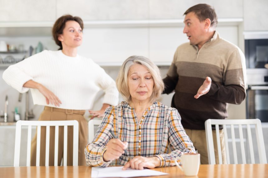 Old woman deciding and signing inheritance papers in family circle.