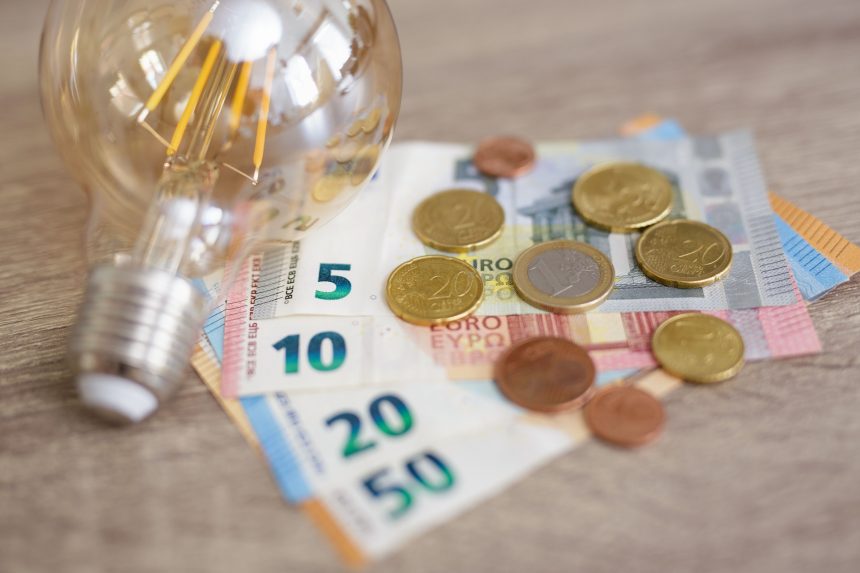 expensive energy bill and rise in electricity prices concept - light bulb with Euro banknotes and coins